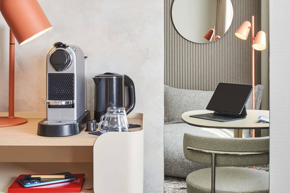 A modern workspace with a desk, laptop, coffee maker, kettle, and a lamp.