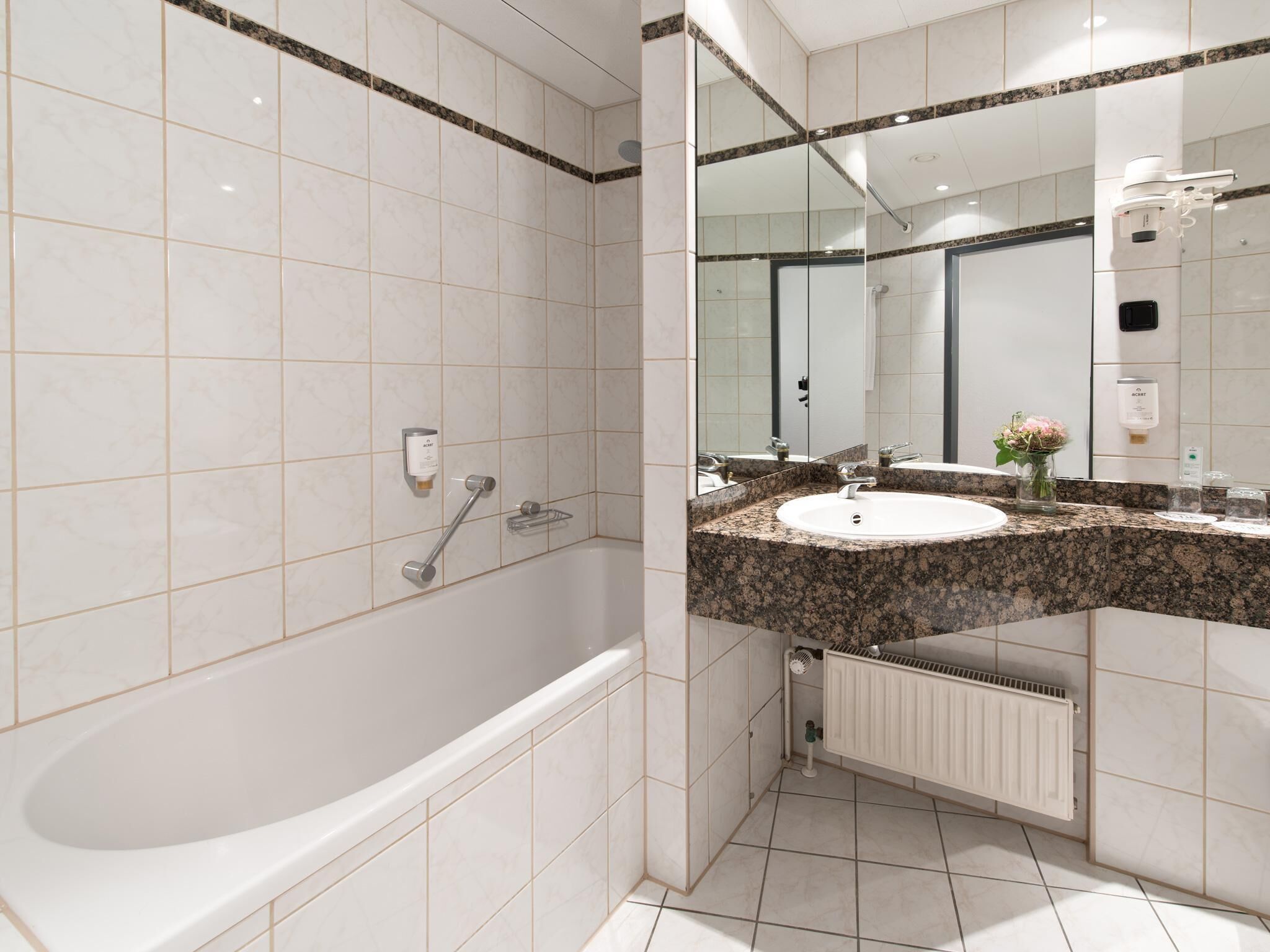 A modern bathroom with a freestanding bathtub, a granite countertop sink, and a large mirror.