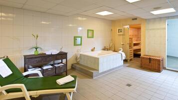 A bathroom with a bathtub, a green chair, a wooden cabinet, and a wicker basket.