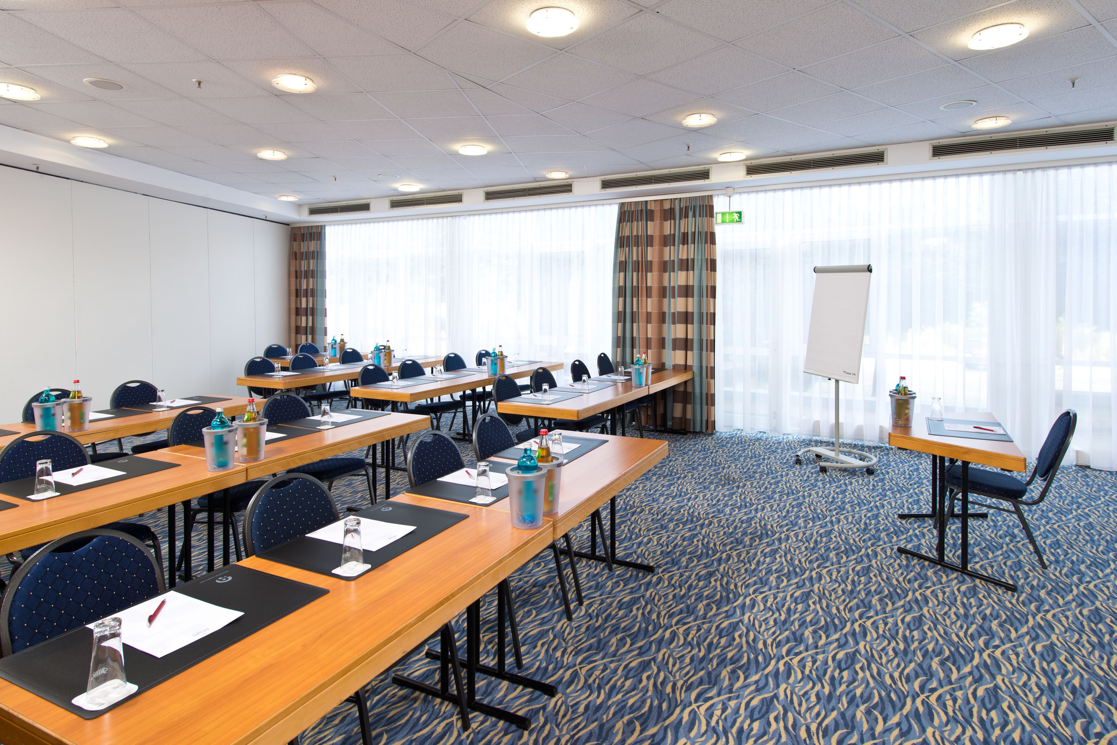 A conference room with multiple tables, chairs, and a whiteboard.
