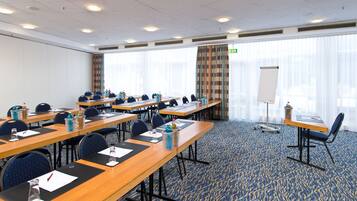 A conference room with multiple tables, chairs, and a whiteboard.