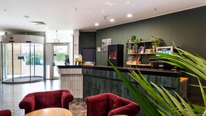 A reception area with a counter, seating, and a green wall. - ACHAT Hotel Bochum Dortmund (Bochum)