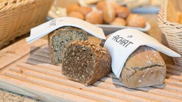 A variety of breads displayed on a wooden board with baskets in the background.