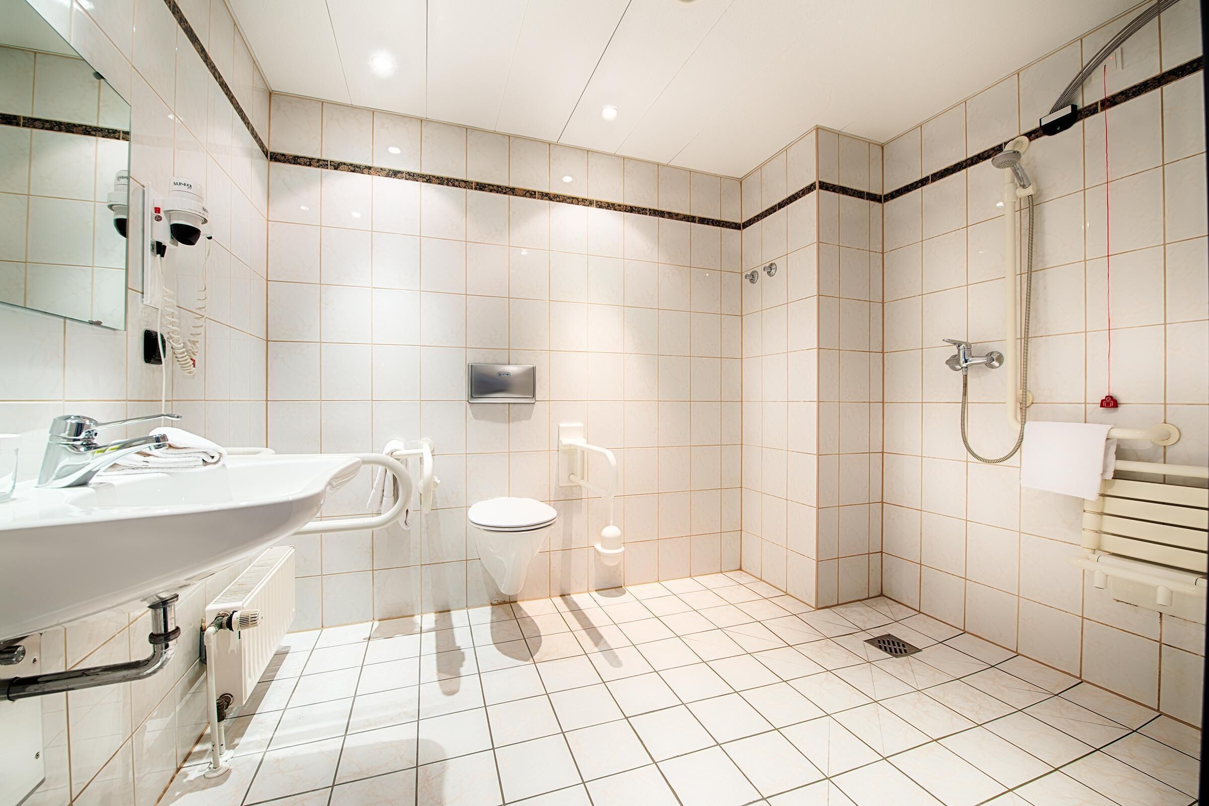 Et moderne badeværelse med vask, toilet og bruser.