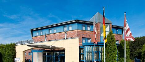 A hotel with a modern design, featuring a brick facade, large windows, and a covered entrance.