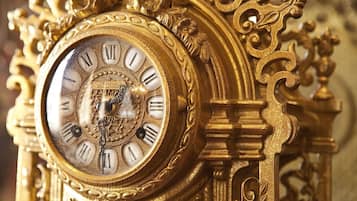 A close-up of an ornate, gold-colored clock with Roman numerals and intricate designs.