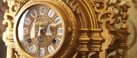 Primer plano de un reloj ornamentado, dorado, con números romanos y diseños intrincados.