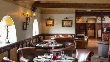 A restaurant with wooden beams, leather chairs, and tables set for dining.