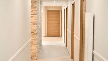 A hallway with a wooden door labeled "CABINE 1", white walls, and a stone accent wall.
