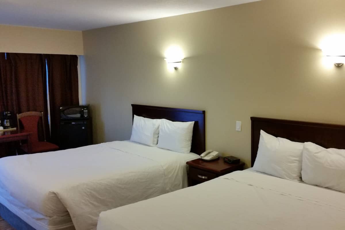A hotel room with two beds, a desk, a chair, and a minibar.