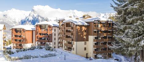 A snow-covered mountain resort with multi-story buildings, balconies, and a snowy landscape.