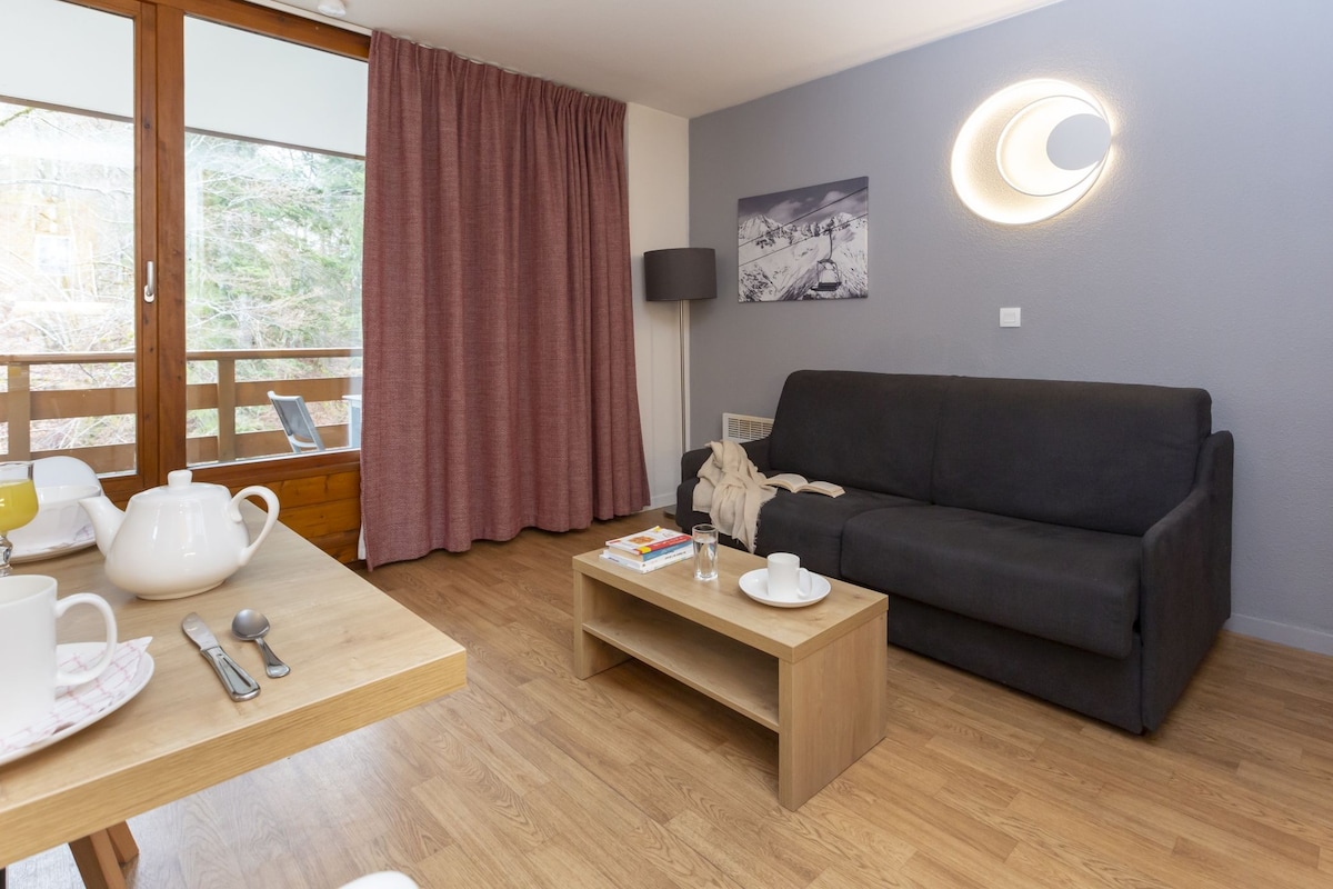 A modern living room with a sofa, a coffee table, a dining table with a teapot, cups, and books.