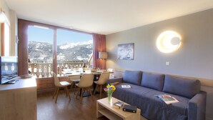 Et moderne hotelværelse med balkon, spiseplads, sofa og TV.