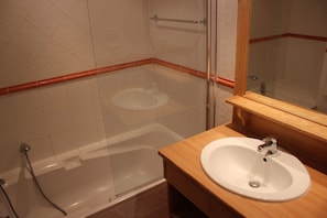 Un baño con bañera, lavabo y espejo.