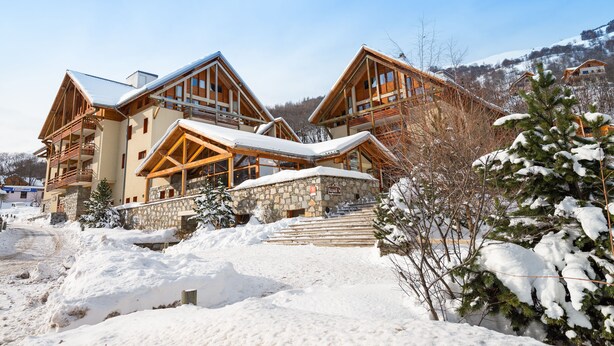 Eine Lodge mit einer Steinfassade, hölzernen Balkonen und einer schneebedeckten Landschaft.