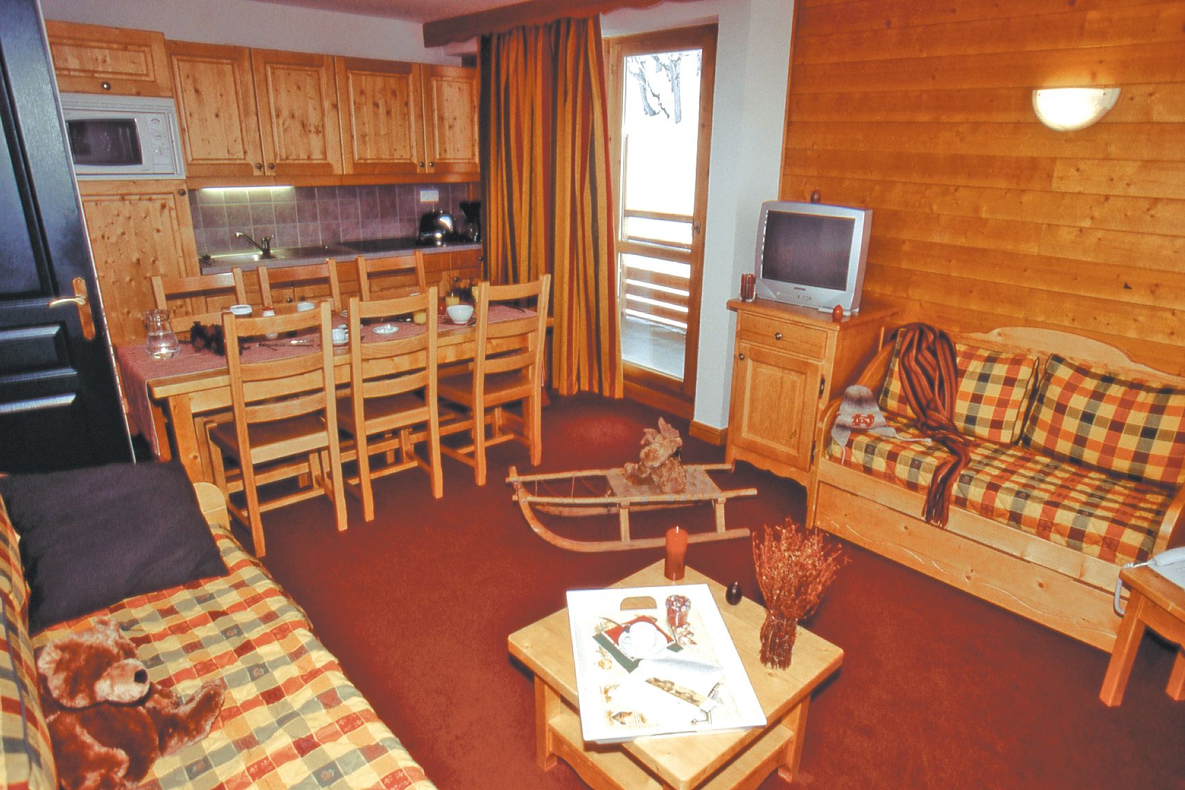 A cozy cabin interior with wooden furniture, a dining area, a television, and a fireplace.