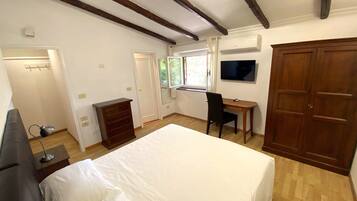 A bedroom with a bed, a desk, a chair, a wardrobe, and a TV.
