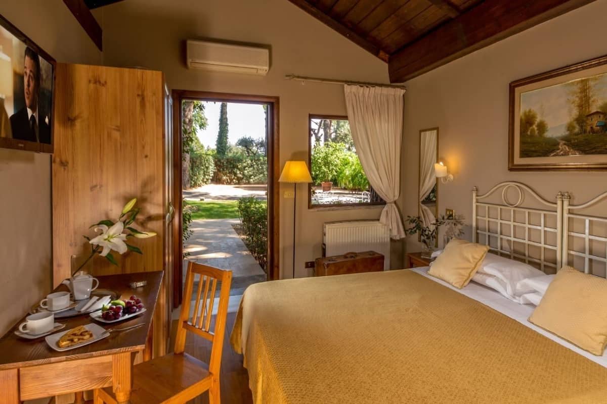 A bedroom with a bed, bedside table, lamp, and a painting on the wall.