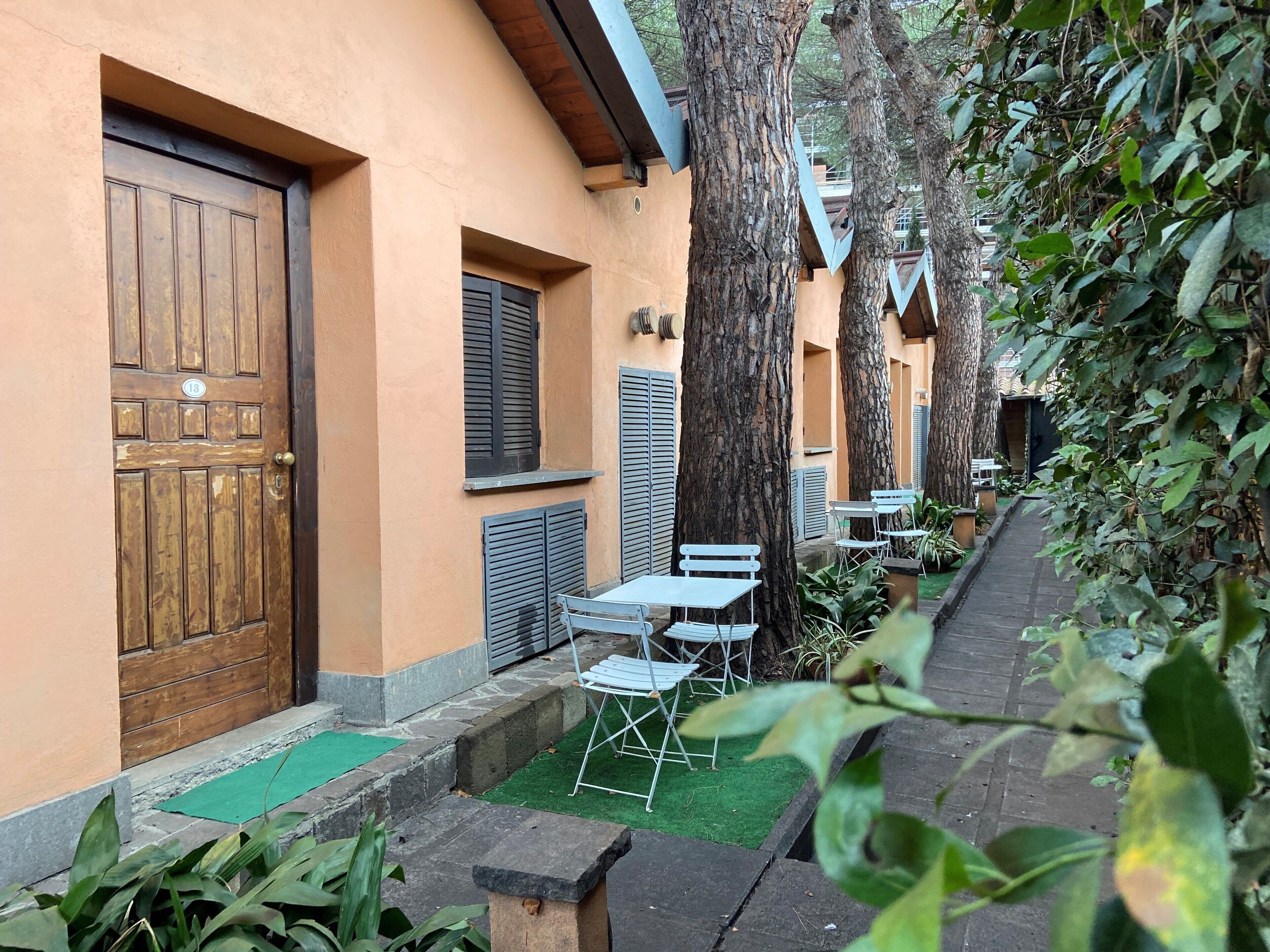 A courtyard with a wooden door, a small table with chairs, and a tree.