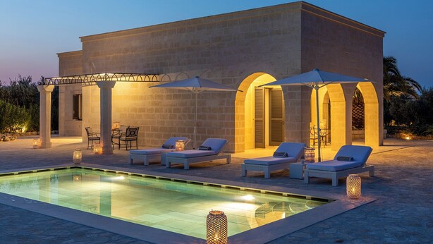 A modern building with a swimming pool, sun loungers, and outdoor seating. - Masseria San Domenico (Fasano)