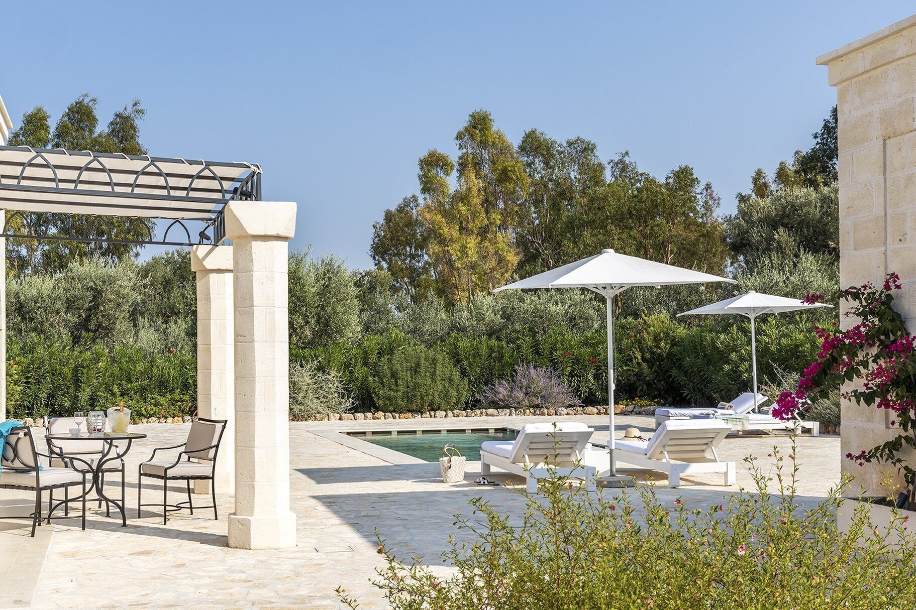 Un espace aménagé au bord de la piscine, avec des chaises longues, des parasols et une pergola.