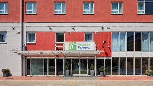 A Holiday Inn Express building with a red facade, large windows, and a clear entrance. - Holiday Inn Express London - Limehouse by IHG (London)