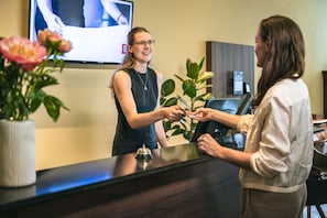 Een receptiebalie met een televisiescherm, een plant en een vaas met bloemen.
