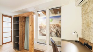 A room with a wooden wardrobe, a sliding glass door, a desk with a lamp, and a radiator. - Tailormade Hotel RÜDEN Schaffhausen (Schaffhausen)