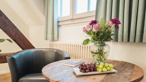 A round wooden table with a vase of flowers and a plate of grapes. - Tailormade Hotel RÜDEN Schaffhausen (Schaffhausen)
