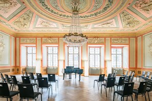 A grand hall with a large chandelier, ornate ceiling, and a piano. - Tailormade Hotel RÜDEN Schaffhausen (Schaffhausen)