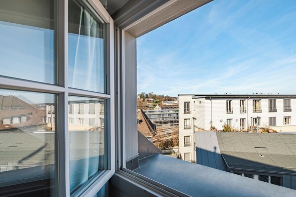 A view from a window overlooking a building with multiple floors and balconies. - Tailormade Hotel RÜDEN Schaffhausen (Schaffhausen)