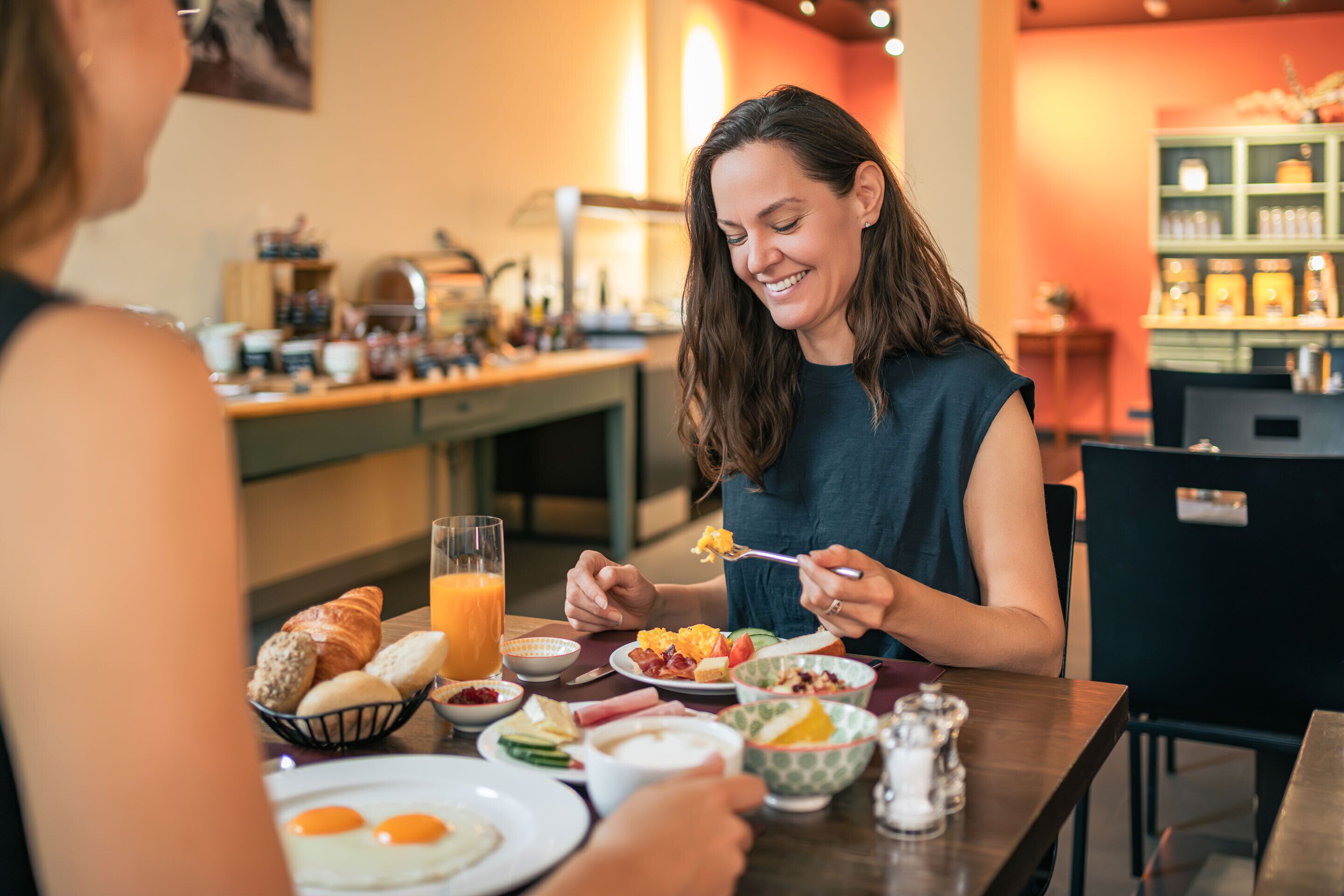 A breakfast setting with a variety of food items and a glass of orange juice on a table.