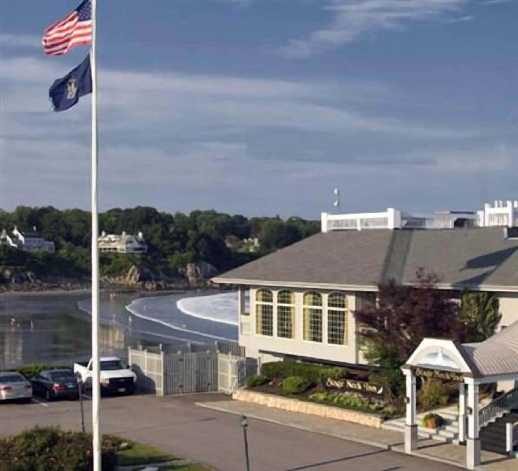 A coastal building with a white facade, large windows, and a small adjacent structure with a dome roof.