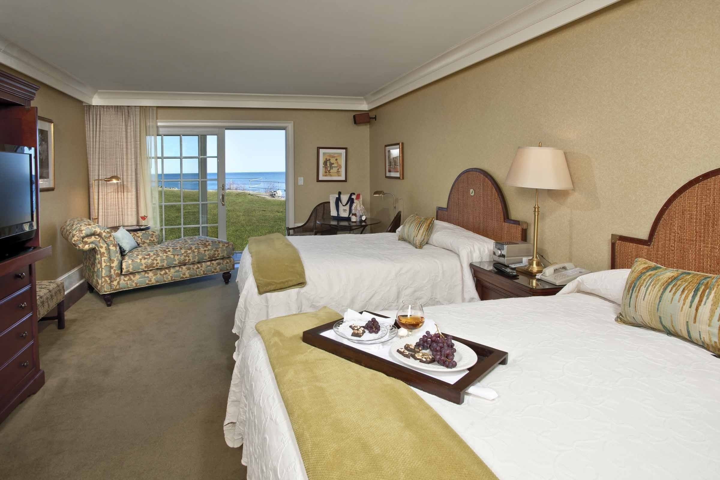 A hotel room with two beds, a sofa, a TV, and a dining table with food.