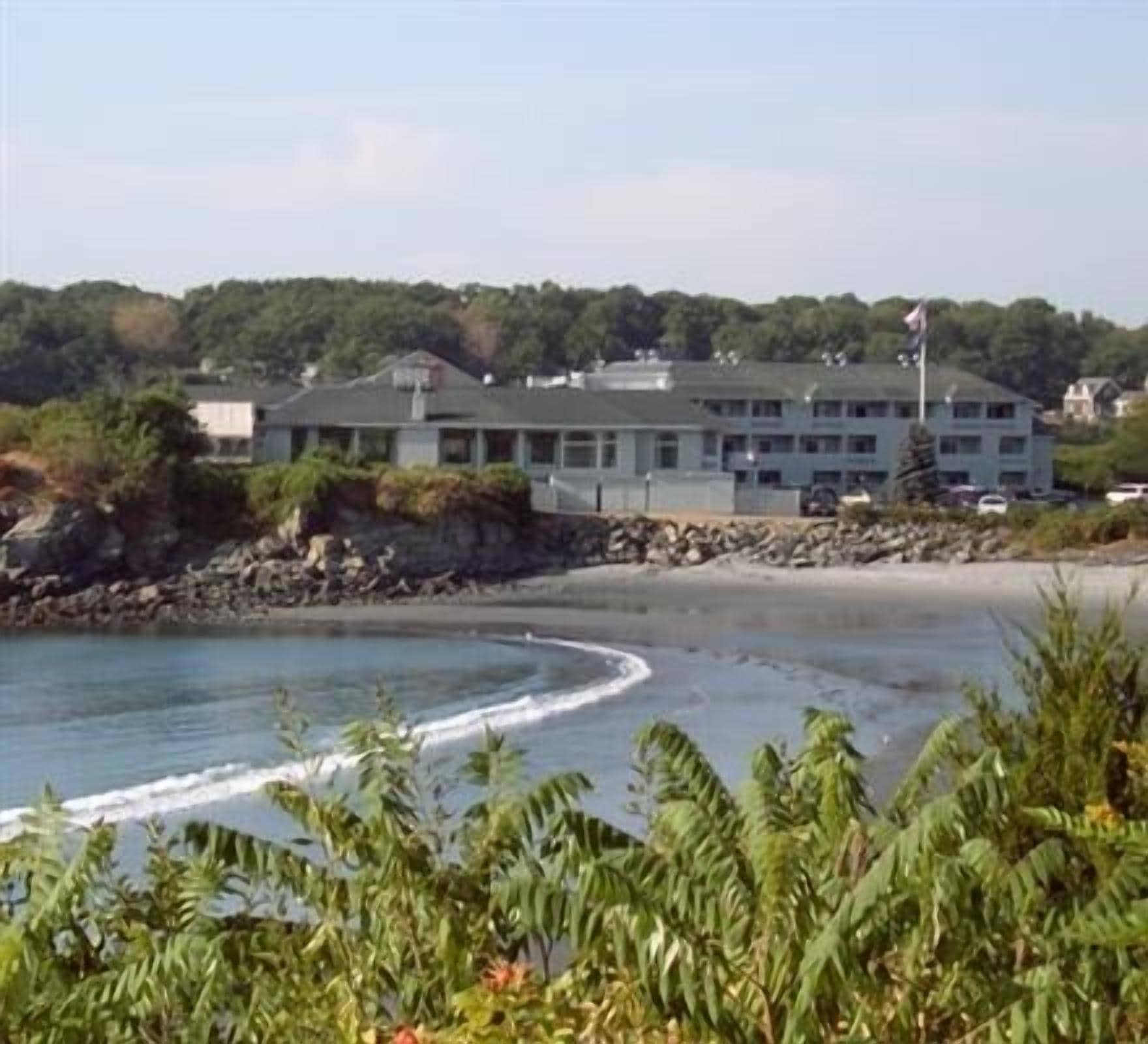A coastal building with a flat roof, multiple windows, and a flagpole.