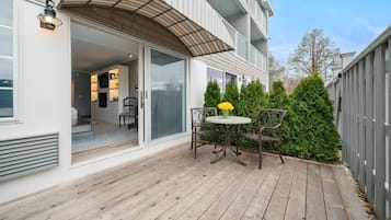 A wooden deck with a table and chairs, a covered patio area, and a view of the interior of a house.