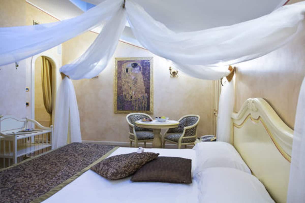 A bedroom with a bed, a small table, two chairs, and a painting on the wall.