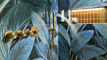 Eine Dusche mit goldenem Wasserhahn und einer Glasscheibe.