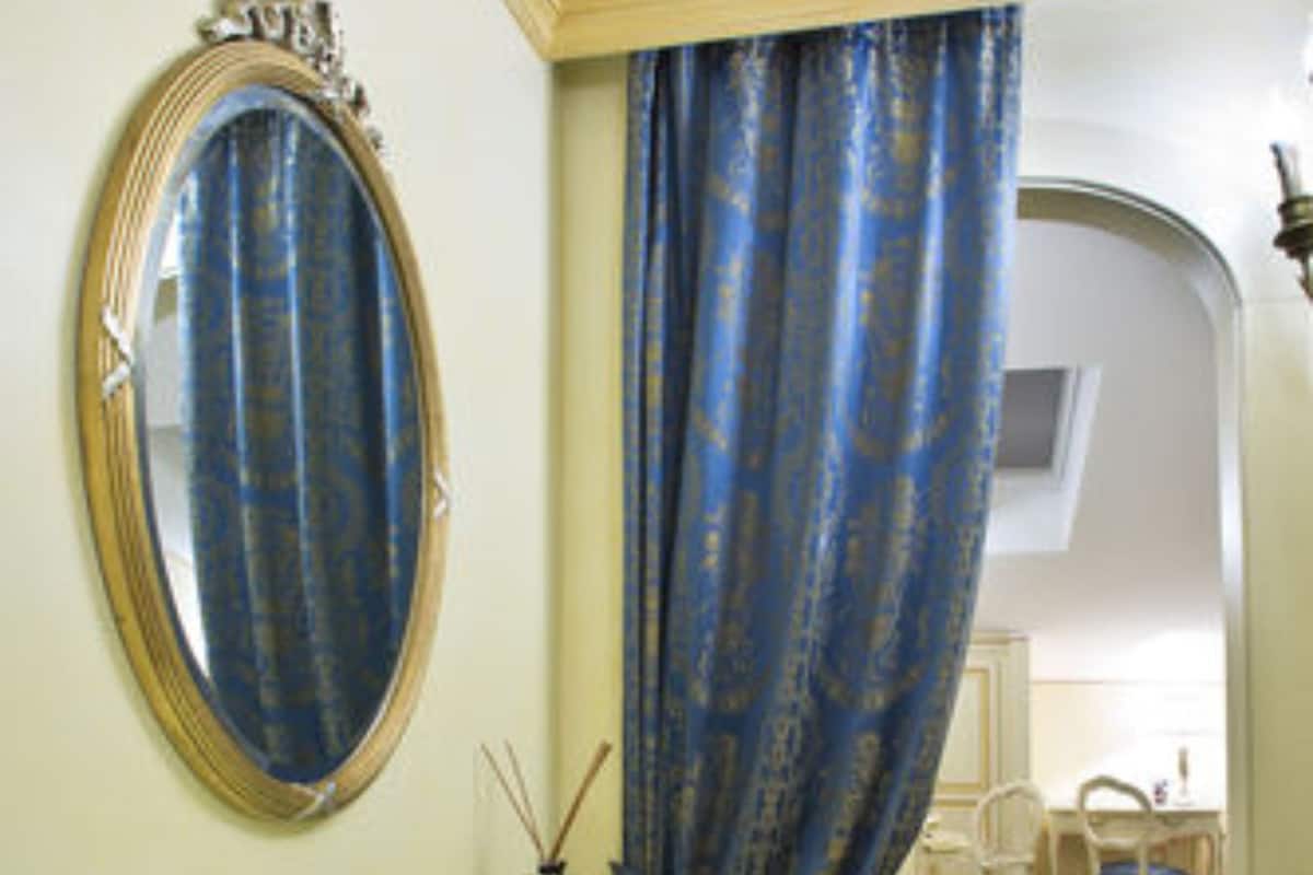 A room with a vanity, a mirror, a bed, and a chair.
