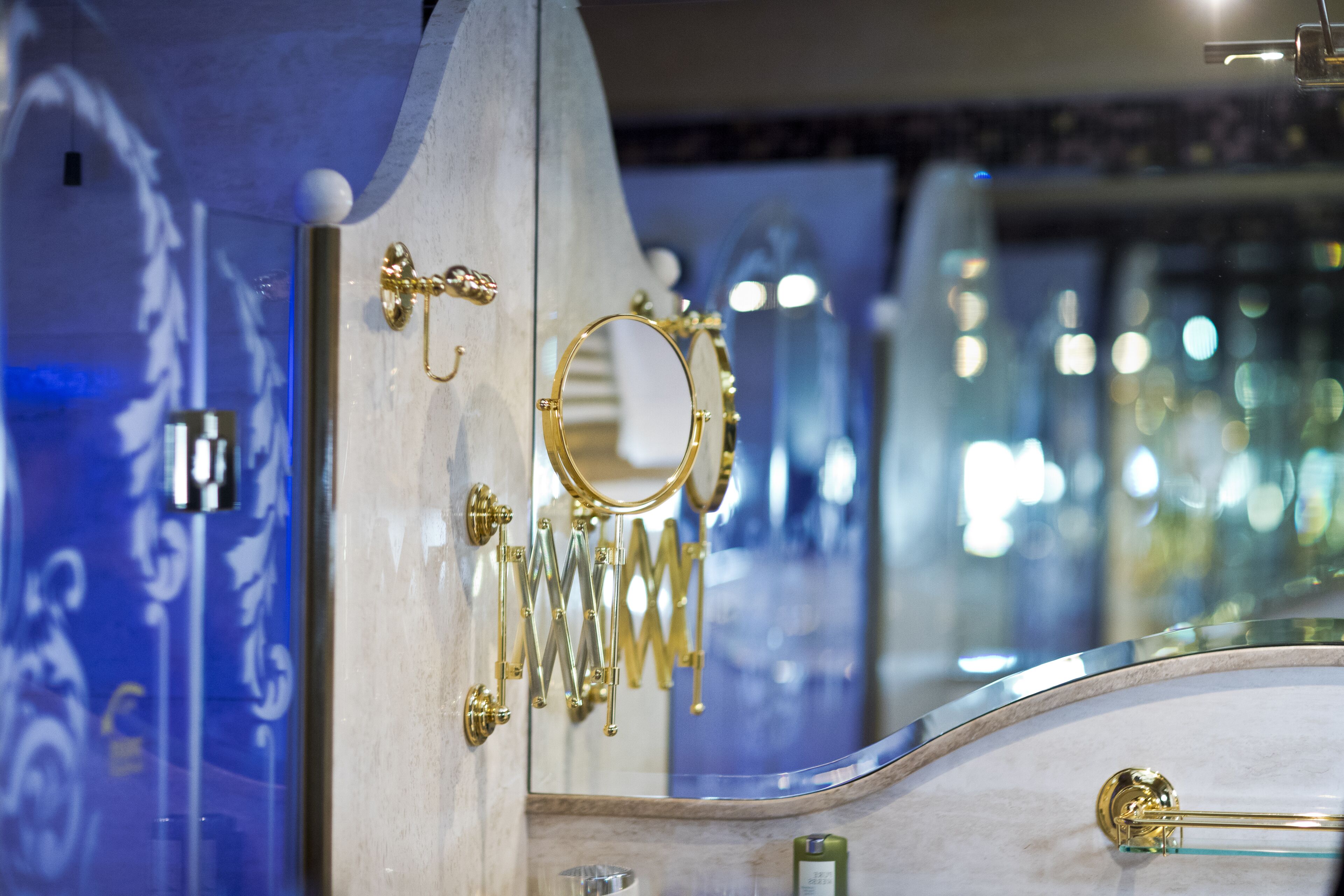 A bathroom vanity with a mirror, gold fixtures, and a marble countertop.
