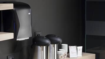 A modern kitchen area with a coffee machine, stainless steel containers, and a wooden counter.