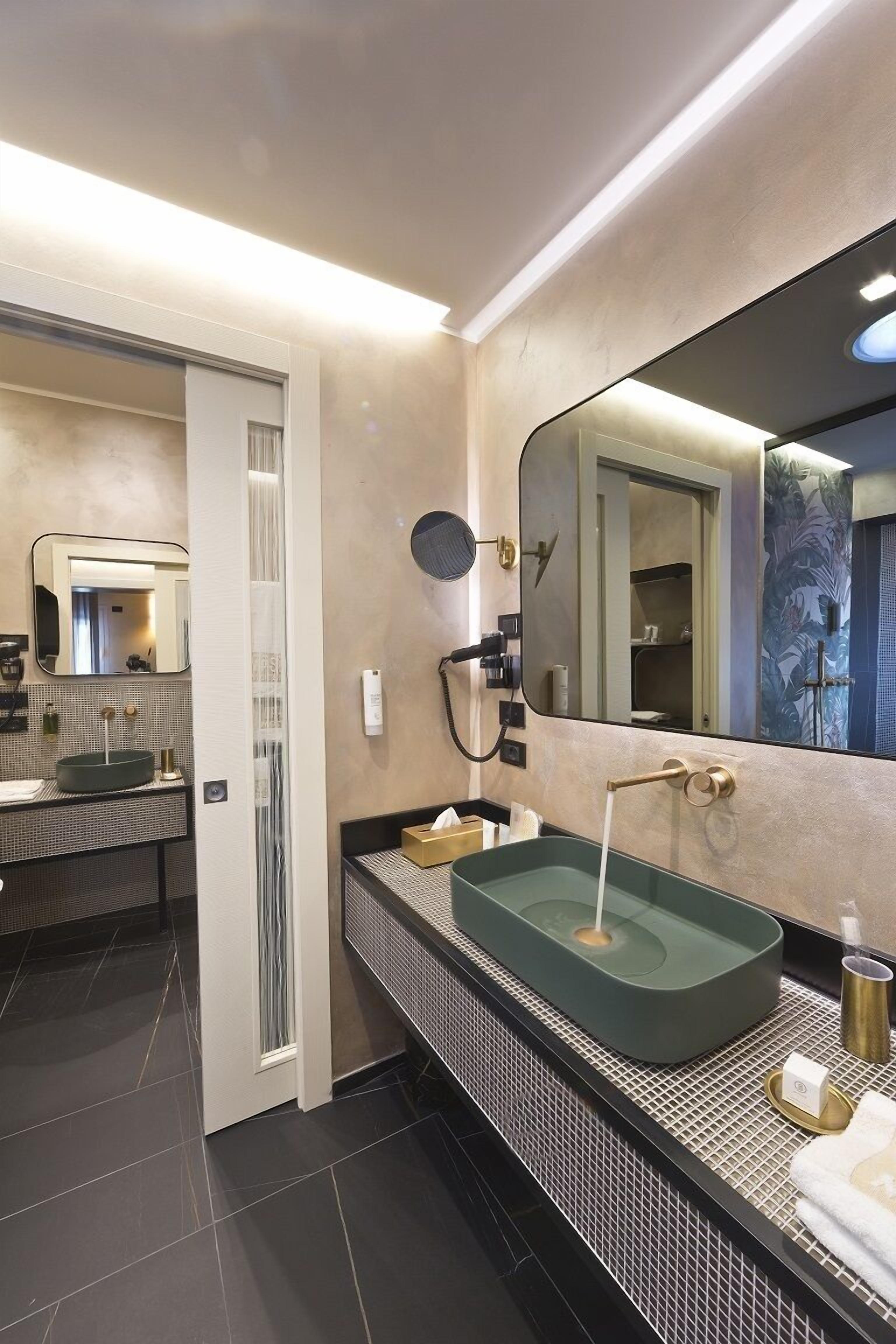 A modern bathroom with a large mirror, a freestanding sink, and a walk-in shower.