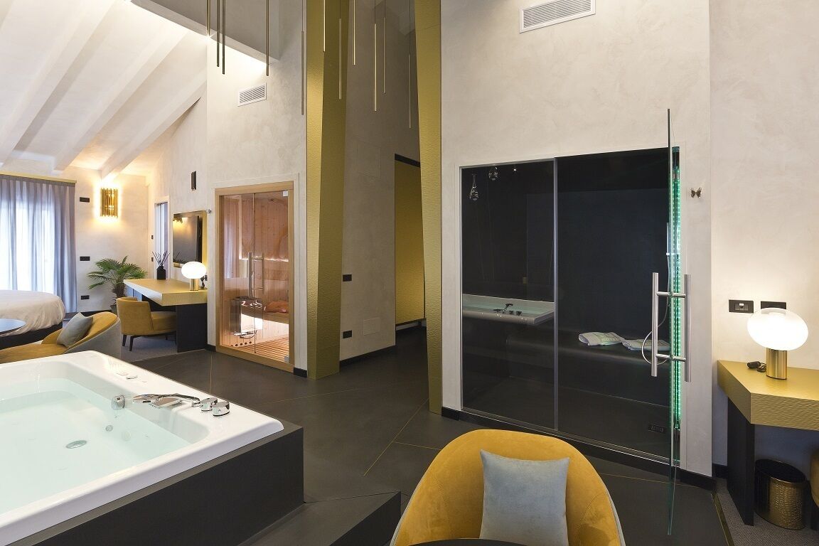 A modern hotel room with a large bathtub, a separate shower area, a dining area, and a cozy seating space.