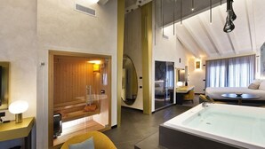 Una camera d'albergo moderna con una vasca da bagno ampia, una sauna in legno e un'area salotto accogliente.