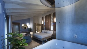 Camera moderna con un letto grande, bagno separato con vasca e una pianta in vaso.