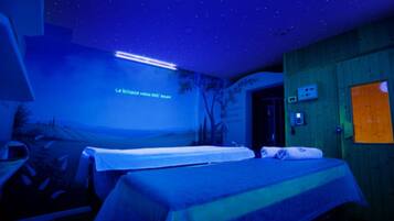 Une pièce comprenant un lit, un bureau et un projecteur mural.