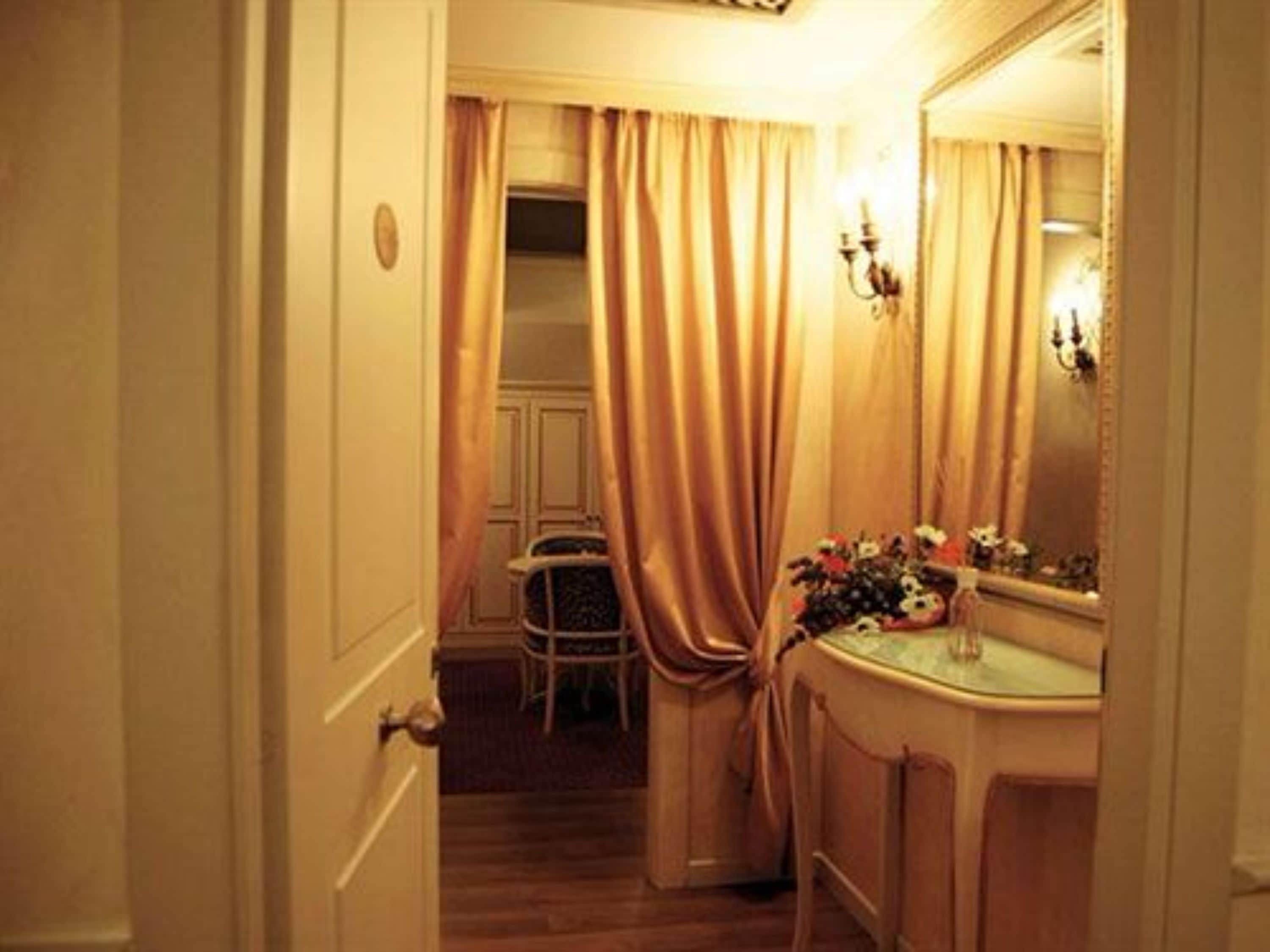 Un pasillo estrecho que conduce a un baño con tocador, espejo y una silla.
