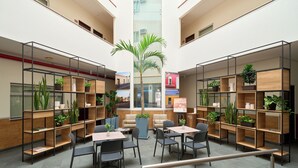 Un espacio interior moderno con asientos, plantas y un árbol central.
