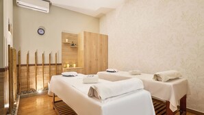 Un cuarto de spa con dos camas, un armario de madera, un reloj y una pared con diseño de hojas.