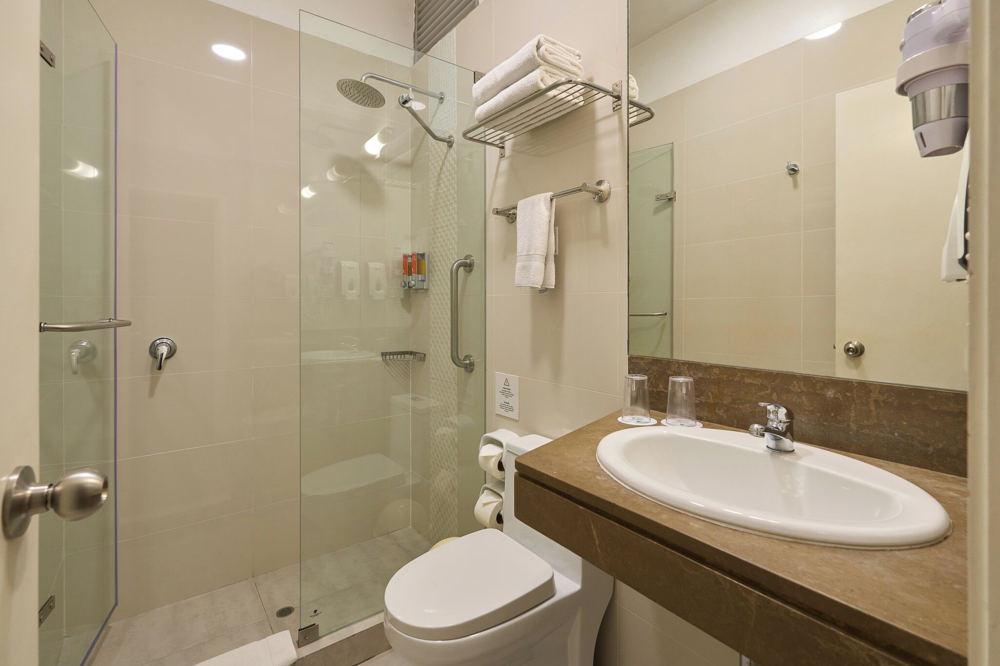 A modern bathroom with a glass-enclosed shower, a white toilet, a sink with a marble countertop, and a towel rack.